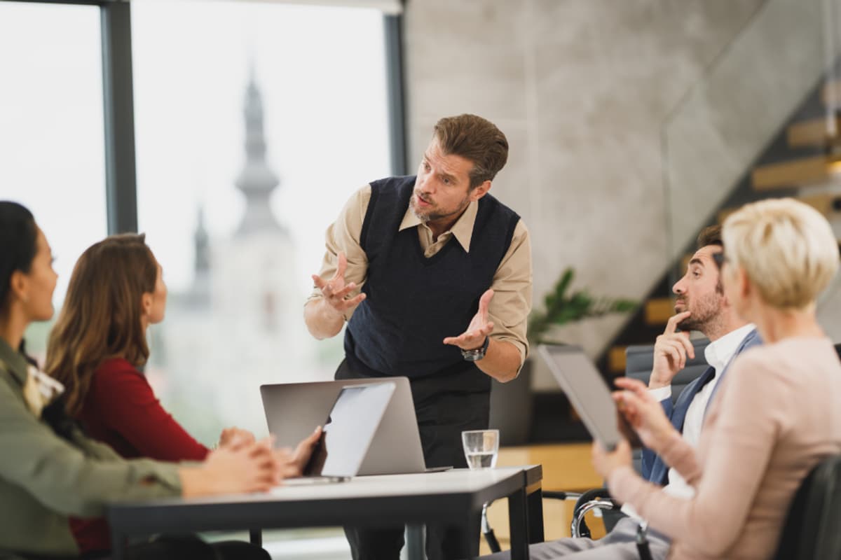 A consultant talking through a plan with a client team around a boardroom table
